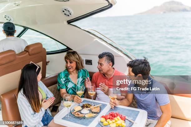 family drinking wine and talking during a yacht trip - pacific_plate stock pictures, royalty-free photos & images