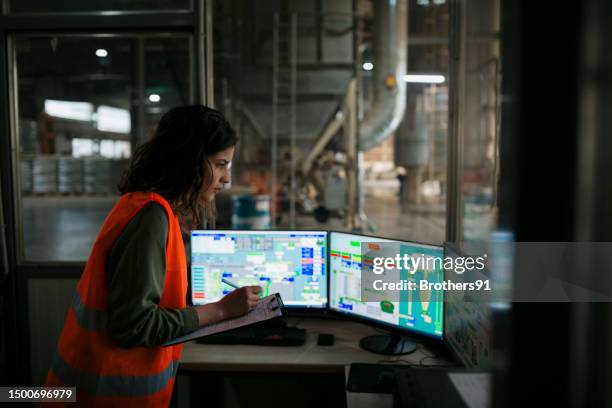 tecnico donna che monitora la produzione dalla sala di controllo della fabbrica del legno - pellet foto e immagini stock