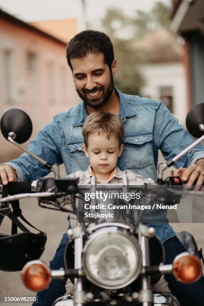 a happy father with his son drives a motorcycle - 4 wheel motorbike stock pictures, royalty-free photos & images