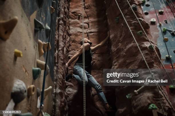 strong man free climbing a indoor climbing wall - freiklettern stock-fotos und bilder