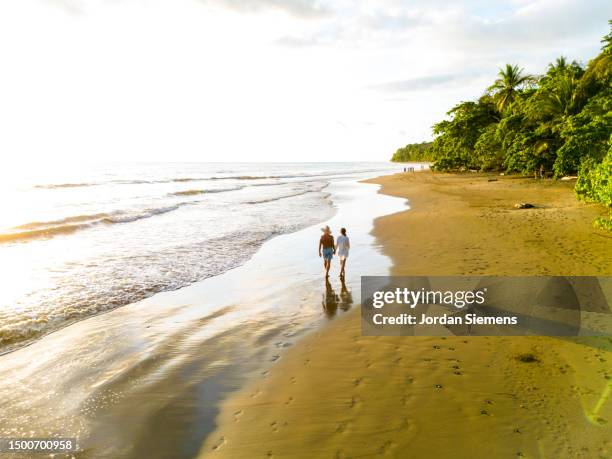 an aerial view of a couple walking along a beach in costa rica - costa rica aerial stock pictures, royalty-free photos & images