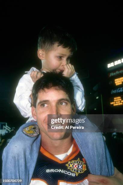 Wide Receiver Ed McCaffrey of the Denver Broncos celebrates with his child after the Super Bowl XXXII game between the Green Bay Packers v the Denver...