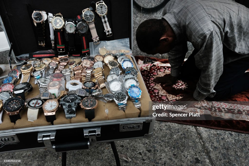 A man prays near knock-off luxury watches displayed by sellers