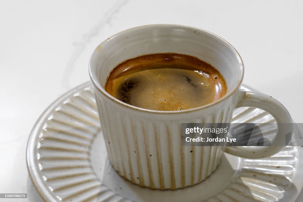 High angle view of a cup of long black coffee on white table