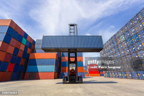 forklift truck lifting up cargo container in shipping yard with blue sky background. - box lifting technique stock-fotos und bilder