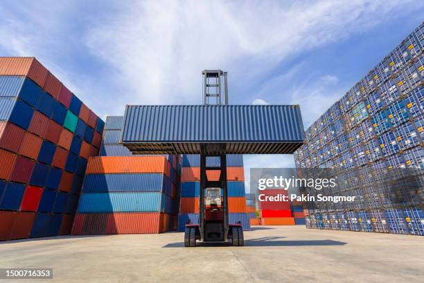 forklift truck lifting up cargo container in shipping yard with blue sky background. - skybox stockfoto's en -beelden