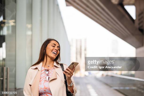 business woman laughing using smartphone - chilean ethnicity stock pictures, royalty-free photos & images