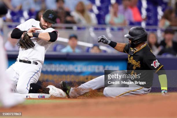 Carlos Santana of the Pittsburgh Pirates slides to safe to third base against Jon Berti of the Miami Marlins during the fourth inning at loanDepot...