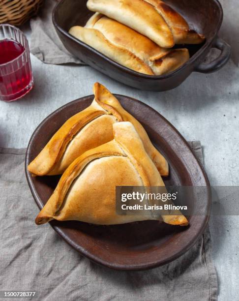 tipical chilean baked empanadas de pino y napolitano on clay plates from pomaire with wine. dish on independence day chile, 18 september party, gray background - día de la independencia fotografías e imágenes de stock