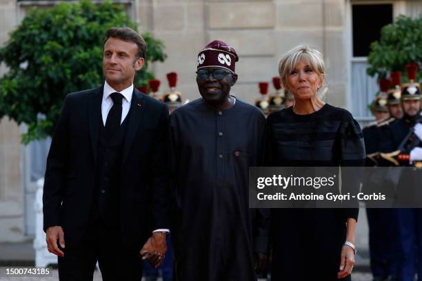 French President Emmanuel Macron and his wife Brigitte Macron greet Nigerian President President Bola Tinubu upon arrival for an official dinner at...