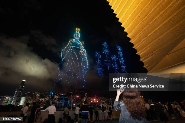 People watch a performance of unmanned aerial vehicles to celebrate the Dragon Boat Festival at Hong Kong Palace Museum on June 22, 2023 in Hong...