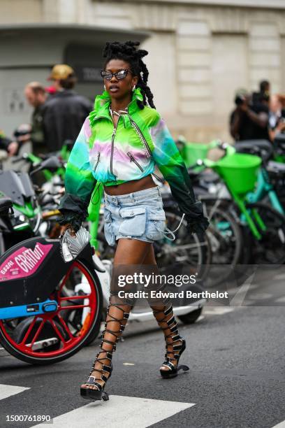 Guest wears black butterfly sunglasses, silver large earrings, a neon green / pale purple / white / blue tie and dye print pattern nylon high neck /...