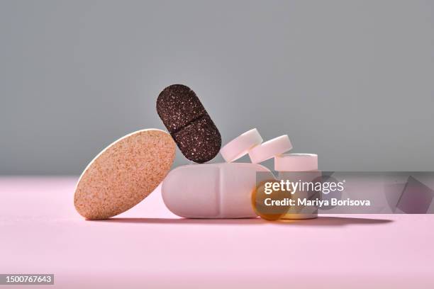 pills, vitamins and nutritional supplements on a pink background are stacked in bizarre figures. - streptomyces antibioticus imagens e fotografias de stock