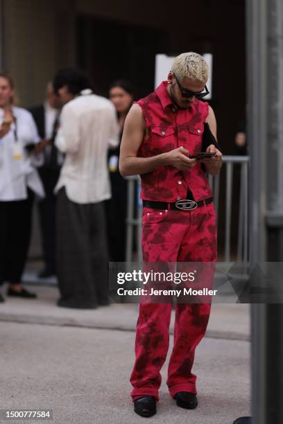 Fashion Week guest is seen wearing a matching denim pink tie dye tow piece with a denim vest and long denim pants, Diesel silver leather belt and...