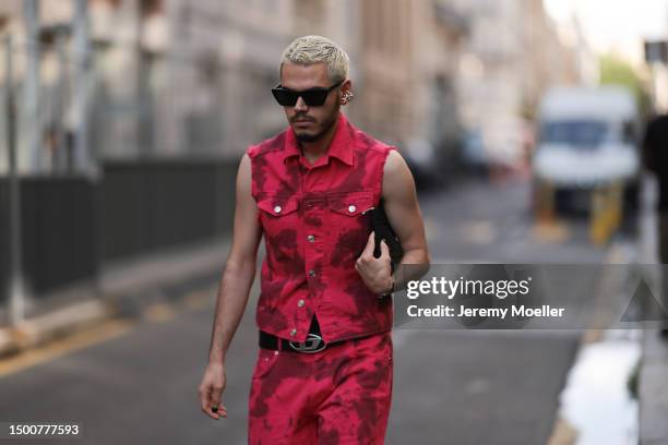 Fashion Week guest is seen wearing a matching denim pink tie dye tow piece with a denim vest and long denim pants, Diesel silver leather belt and...