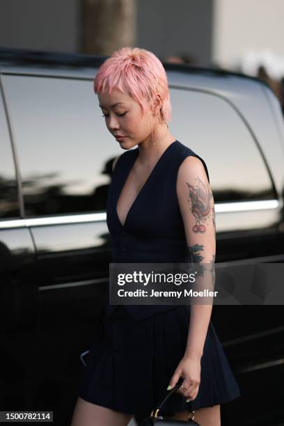 Xiaorui Kong is seen wearing gold heart big earrings, navy blue vest, plisee matching mini skirt and Ami Paris gold and black leather bag outside Ami...