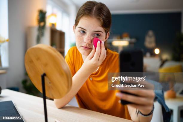 teenage girl texting messages on her phone while doing make-up - powder puff stock pictures, royalty-free photos & images