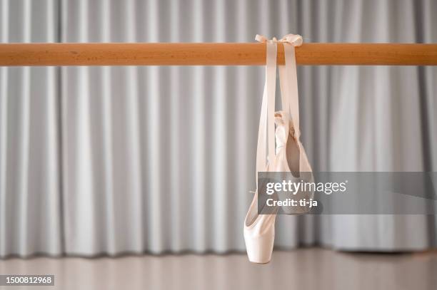 pair of pink ballet shoes hanging on a wooden barre - pointe stock pictures, royalty-free photos & images