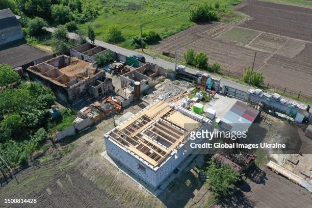 In an aerial view, a new residence is under construction next to a house destroyed due to hostilities on June 16, 2023 in Velyka Dymerka, Kyiv...
