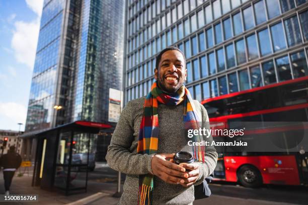 happy adult black male drinking coffee while walking on a city street - coffee to go cups stock pictures, royalty-free photos & images