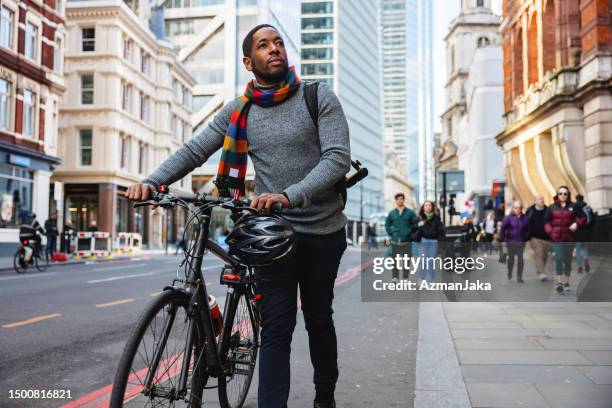 serious adult black male walking home from the office with a bike - man bicycle stock pictures, royalty-free photos & images