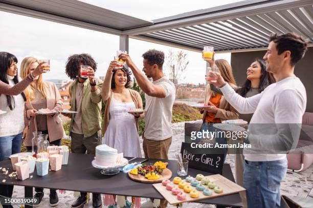 diverse group of adult friends toasting at a gender reveal party in the summer - outdoor baby shower stock pictures, royalty-free photos & images