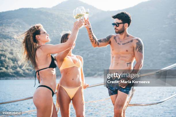 friends clink glasses of wine at sunset on a boat. - beach party stock pictures, royalty-free photos & images