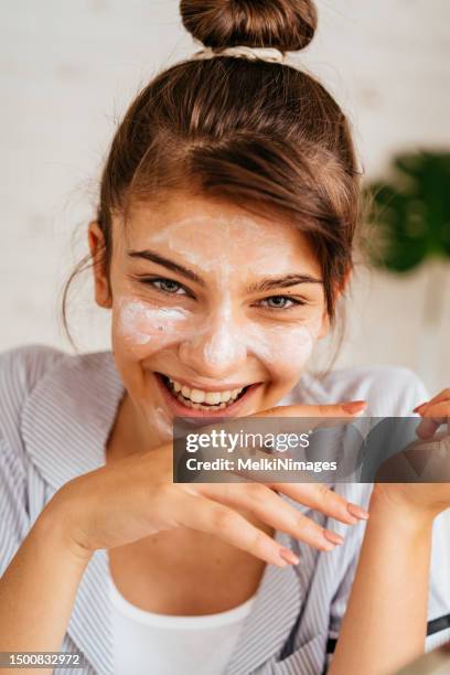 young woman doing routine skin care at home with beauty products - facial stock pictures, royalty-free photos & images