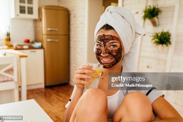 young woman sitting at the desk and drinking lemonade as a detox morning routine - facial stock pictures, royalty-free photos & images