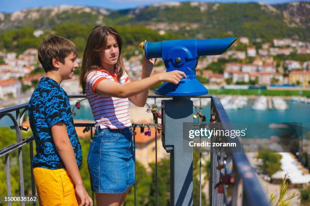 teenage girl and her brother using binoculars on the town viewpoint at the seaside - croatia girls stock pictures, royalty-free photos & images