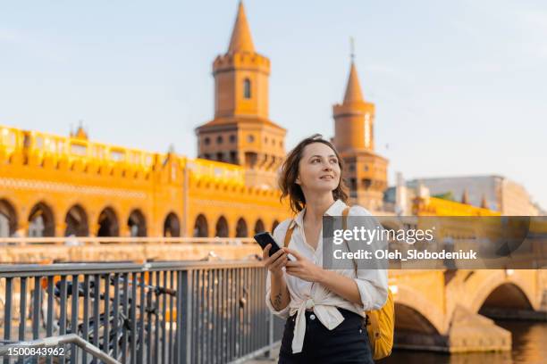 frau mit smartphone beim gehen in berlin - drahtlose technologie stock-fotos und bilder