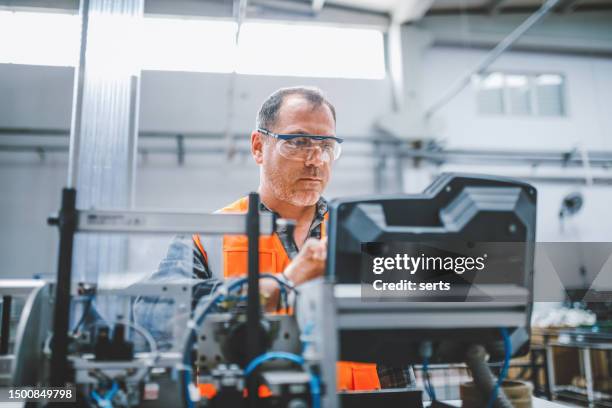 operaio industriale maschio che lavora con attrezzature di produzione in una fabbrica - industria elettronica foto e immagini stock