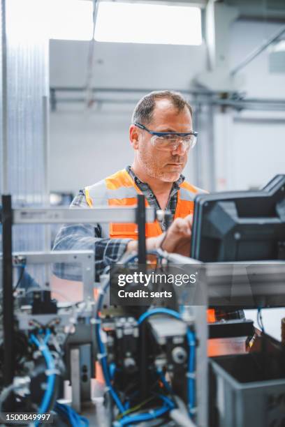 male industrial worker working with manufacturing equipment in a factory - técnica de fotografia imagens e fotografias de stock