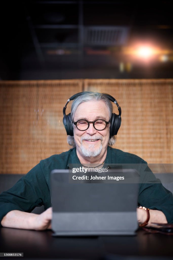 Smiling senior man with headphones using tablet