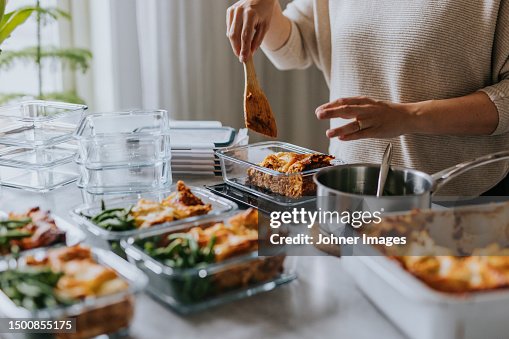 Woman weighing lunch boxes as part of healthy meal prep Woman weighing lunch boxes as part of healthy meal prep