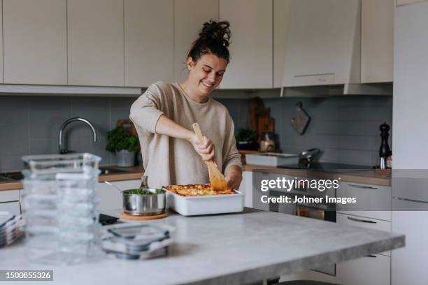 happy woman portioning lasagna as part of meal prep - regarder vers le bas photos et images de collection