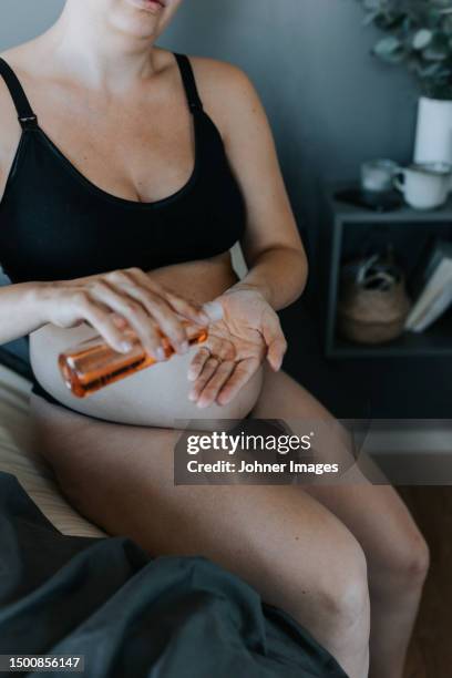 pregnant woman doing body care routine - mid volwassen vrouw stockfoto's en -beelden