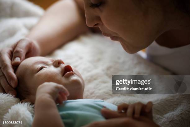 happy mother playing in bed with her baby - newborn stock pictures, royalty-free photos & images