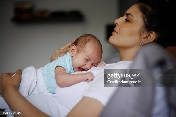madre exhausta sosteniendo a su bebé recién nacido llorando. depresión posparto. - baby depression fotografías e imágenes de stock