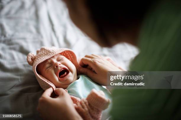 mother dressing clothes to her crying baby girl - moms crying in bed stock pictures, royalty-free photos & images