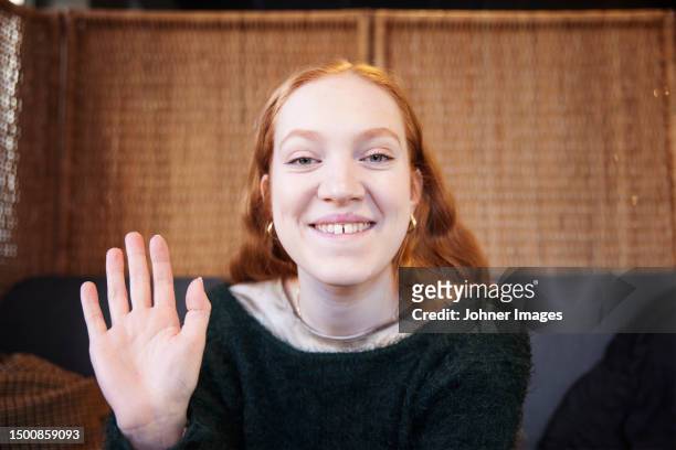 portrait of smiling woman looking and waiving at camera - waving stock pictures, royalty-free photos & images