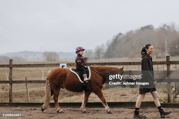 girl horseback riding with female instructor walking along her - england sweden stock pictures, royalty-free photos & images