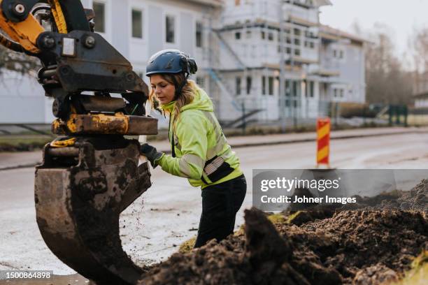 female road worker and excavator at digging site - dirty construction worker stock pictures, royalty-free photos & images
