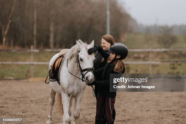 smiling girl standing with horse and looking at camera - enable horse stock-fotos und bilder