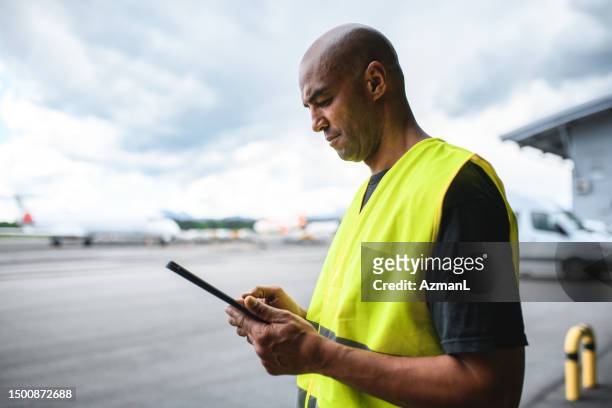 mixed-race-flughafen-bodenbesatzungsmitglied mit digitalem tablet - airport ground crew uniform stock-fotos und bilder