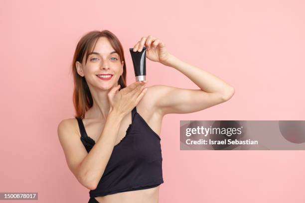 portrait of young blue eyed caucasian woman standing on isolated on pink background holding jar of cosmetic cream. - werbemittel stock-fotos und bilder