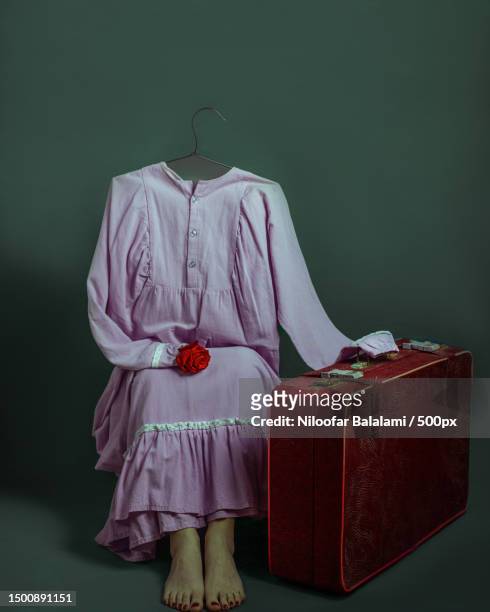 a dress sitting near by a suitcase against dark background,tonekabon,iran - niloofar stock pictures, royalty-free photos & images