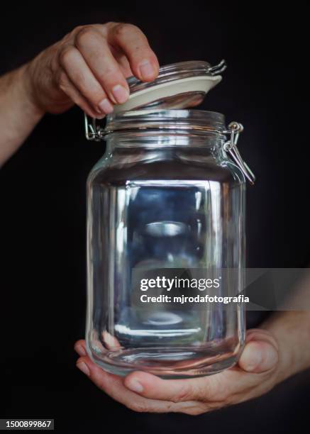 hands holding empty glass jar - キャニスター　ガラス ストックフォトと画像