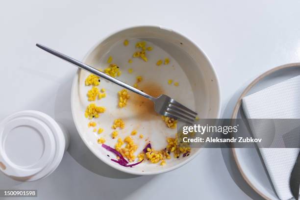 a dirty empty plate and fork on a wooden kitchen or dining table. cutlery is used, symbolizing the end of lunch or dinner. a portion of food eaten, overeating. next to it is a disposable paper coffee mug. completion of lunch or dinner. - the end stock pictures, royalty-free photos & images