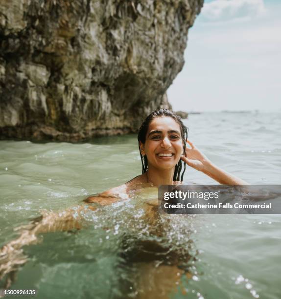 a woman up to her shoulders in the ocean in an idyllic place - strand of human hair stock pictures, royalty-free photos & images